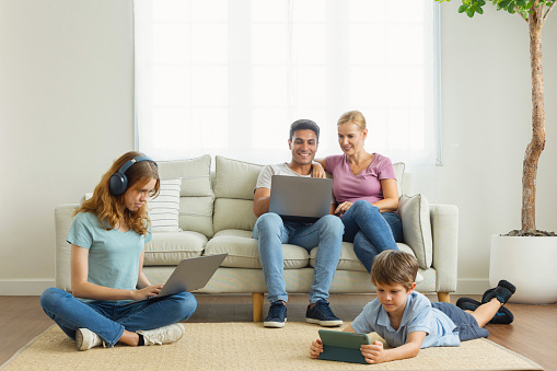 work from home. A parent using a laptop on the couch in the living room. Children use the phone app, search for information, using wifi 5G internet. Family ignore and gadget addiction concept