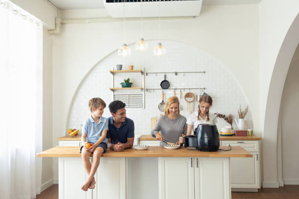 The Caucasian family Make breakfast with the air fryer together.  father, mother, daughter and sons Cooking in the kitchen together at home. Happy family relationship and technology concept stock photo