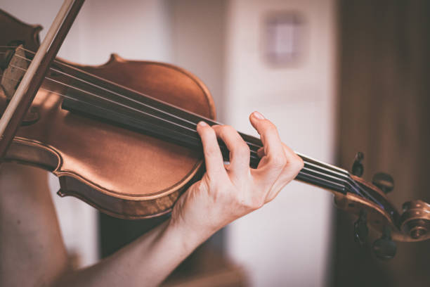 istock Practicing classical music and violin concept: Young girl happily plays on her violin 1320604489