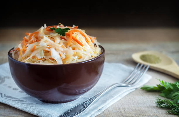 In a ceramic Cup on an old wooden table sauerkraut with carrots.