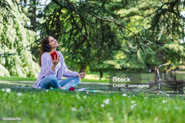 Young Woman With Headphones Listening Music Sitting At The Park Stock Photo - Download Image Now