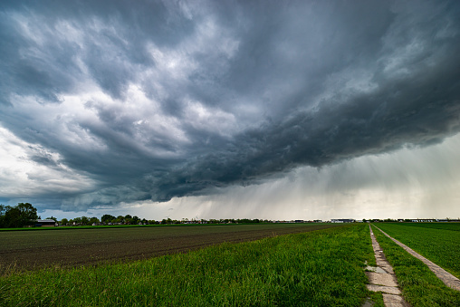 Severe weather is nearby as a storm with developing arcus or shelf cloud is approaching over the Dutch countryside.