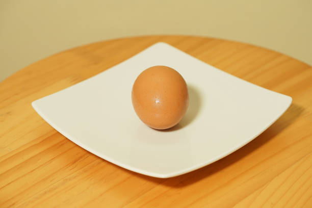 istock A fresh egg on white plate isolated on a wooden background 1320608531