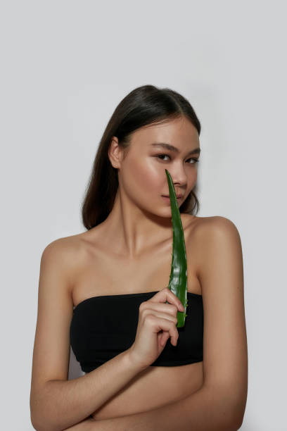 sensual jovem asiática mulher segurando folha de aloe verde - herbal medicine asian ethnicity aloe women - fotografias e filmes do acervo