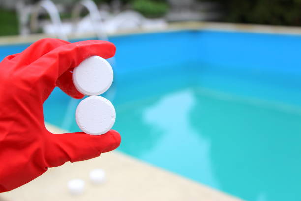 White mini-tablet of chlorine in the hand of the staff for disinfection of swimming pools. The beginning of the swimming season is hot summer. Rubber protective red glove. Water purification. White mini-tablet of chlorine in the hand of the staff for disinfection of swimming pools. The beginning of the swimming season is hot summer. Rubber protective red glove. Water purification. chlorine stock pictures, royalty-free photos & images
