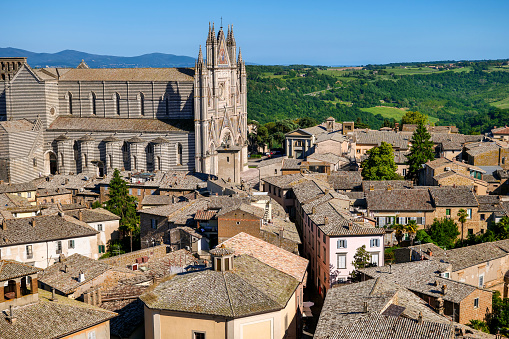 A panoramic view of a portion of the medieval city of Orvieto, in the Umbria region of central Italy, dominates for the majestic Gothic facade of the Basilica di Santa Maria Assunta or Duomo di Orvieto. The construction of the magnificent Duomo, a masterpiece of Italian Gothic art, began in 1290 under the pontificate of Pope Nicholas IV and was completed in the second half of the 15th century. More than 20 artists worked on the magnificent facade of the Cathedral during the two centuries of construction of the church. Image in high definition format.