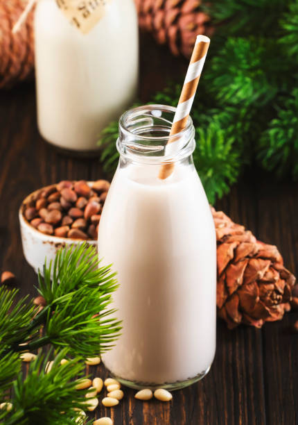 cedar nut milk in bottles, wooden background. non dairy alternative vegan milk and pine cones. healthy vegetarian food and drink - pine nut nut seed vegan food imagens e fotografias de stock