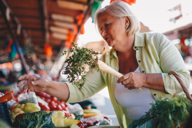 istock Old lady is putting more vegetables in her shopping basket. 1320622836
