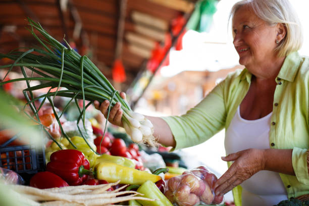 istock Smiling blond senior woman buying fresh leeks. 1320623818