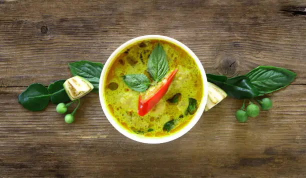 Photo of Top view of green curry fish ball (Thai food) in white bowl on wood table, look delicious.