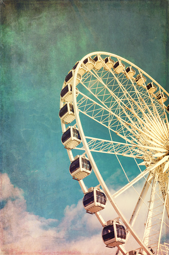 Retro style image of a ferris wheel against blue sky. Cross-processed, grunge effect.