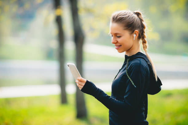 istock Attractive girl using her phone, wireless headphone while running in the park 1320627602