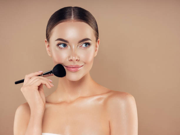istock Beautiful young woman applying foundation powder 1320627648