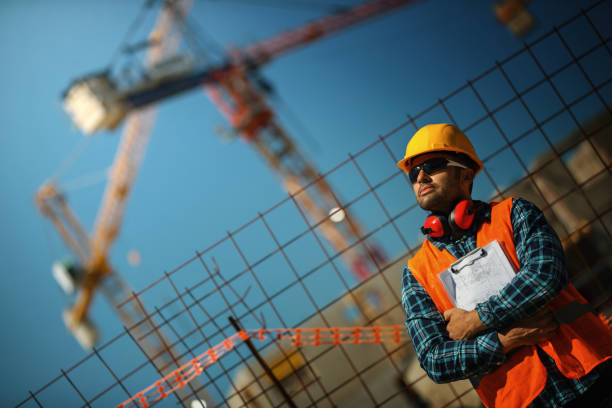 istock Construction worker proudly posing in front of the building site. 1320629592