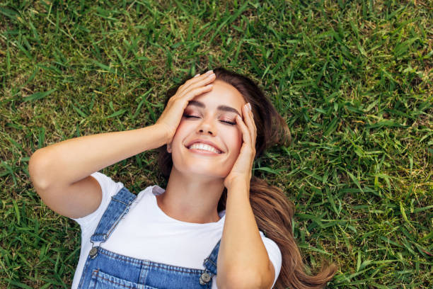 istock High Angle View Of Smiling Young Woman Lying Down On Grass 1320630449