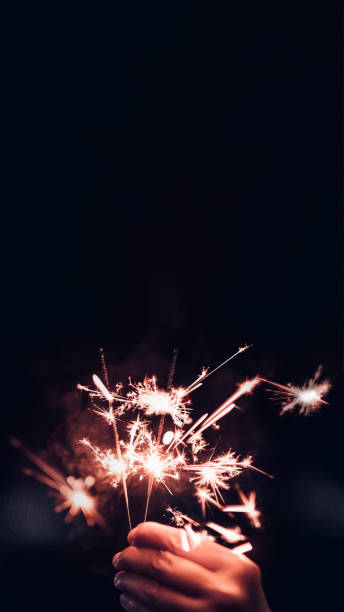 istock Make a wish new year 2022 with hand holding burning Sparkler firework blast with on a black bokeh background at night,holiday celebration event party.vertical ratio 1320630940