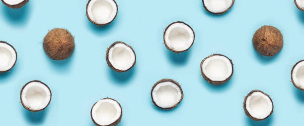 istock many open coconut halves and a leaf of a palm tree on a blue background. Top view, flat lay. Banner 1320633761