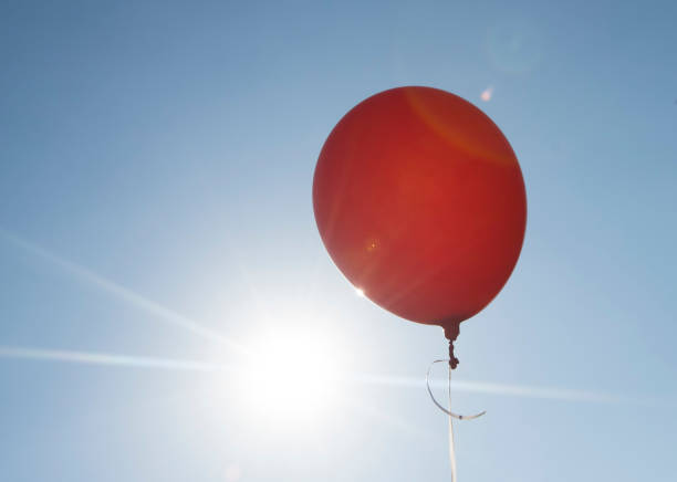 istock red balloon and blue sky background with sun 1320636670