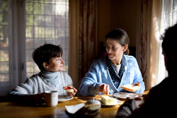 Portrait of happy poor small girl with parents eating indoors at home, poverty concept. A portrait of happy poor sad small girl with parents eating indoors at home, poverty concept. family mother poverty sadness stock pictures, royalty-free photos & images