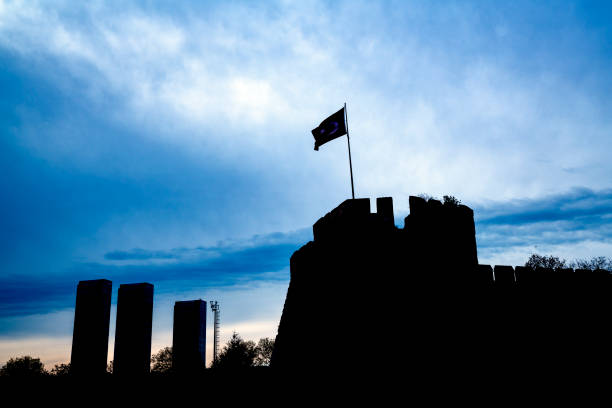 Part of historical Byzantine wall In Istanbul. The wall was photographed in silhouette towards the blue cloudy sky.  There are three skyscrapers the corner of that photo.