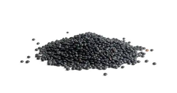 Black lentils isolated. Dry beluga lentil grains pile, heap of raw dal, daal, dhal, masoor, Lens culinaris or Lens esculenta pulse on white background side view