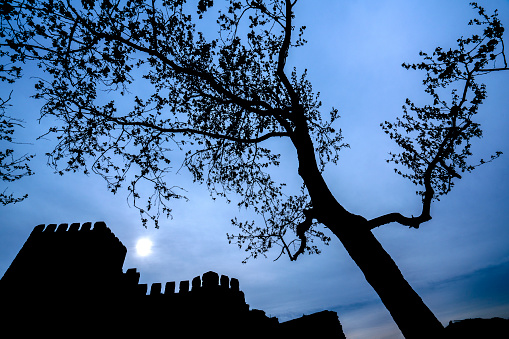 Part of historical Byzantine wall In Istanbul. The wall was photographed in silhouette towards the blue cloudy sky.  There is a minaret the corner of that photo.