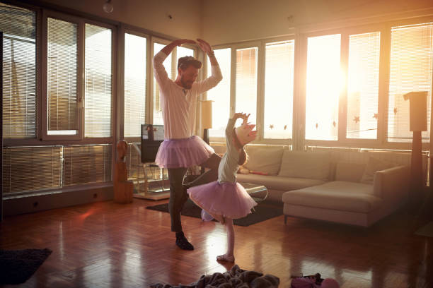 A young Dad and his little daughter practicing ballet moves while they have a training at home together. Family, together, home A young Dad and his little daughter practicing ballet moves while they have a training in a playful atmosphere at home together. Family, together, home dancing dad stock pictures, royalty-free photos & images