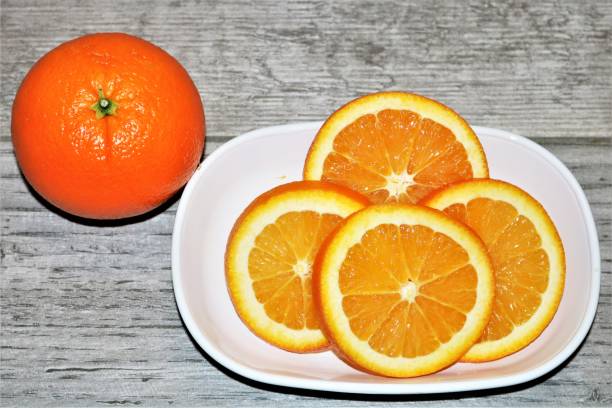istock Orange Sliced in White Dish on Wood Table 1320644514