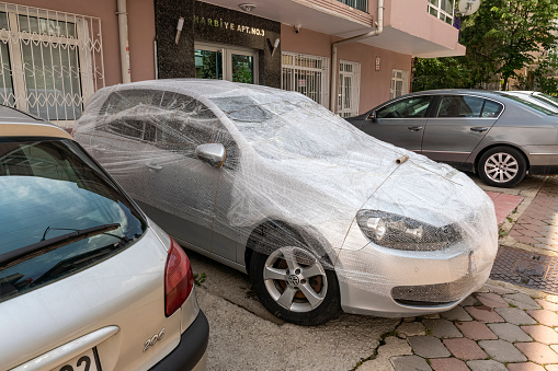 Ankara, Turkey - May 29, 2021: People-type Protection Against Hail. The Ankara Governor's Office said that it will hail hard today, precautions will be taken, and newspapers were published. People is finding different solutions against the extreme weather protections. The man turned it into a gift wrap to protect his car against hail.