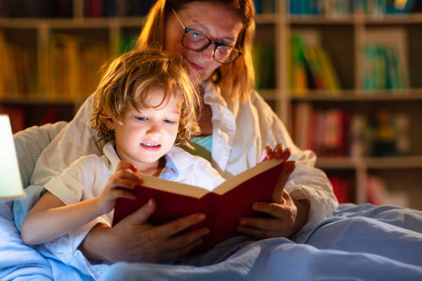 istock Mom and child reading book in bed. Kids read. 1320649280