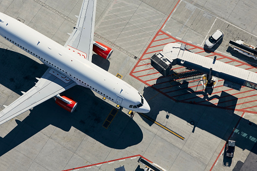 Aerial view of plane. Airplane in front of the passenger boarding bridge from airport terminal.\