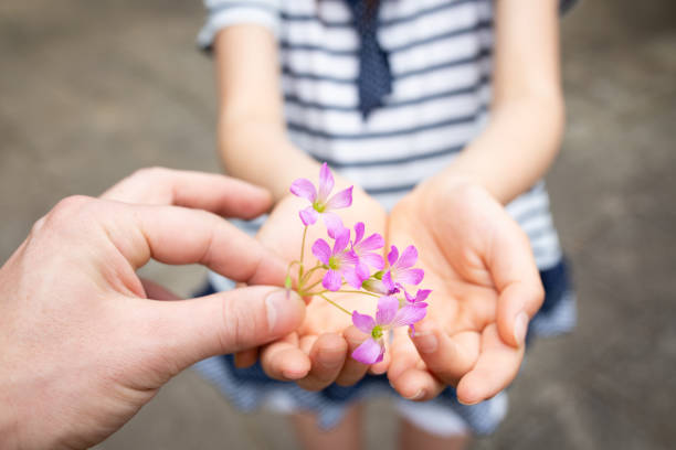 Child giving flowers. Little kid girl holding flowers in hands. Mother's Day concept.