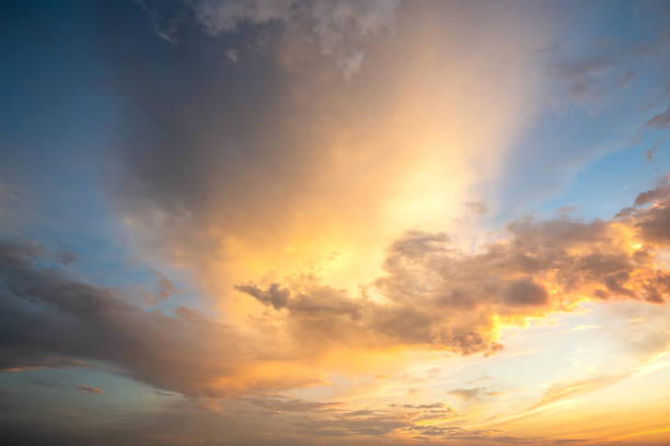 istock Dramatic cloudy sunset landscape with puffy clouds lit by orange setting sun and blue sky. 1320650990