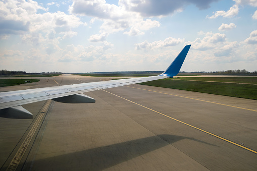View of jet airplane wing taxiing runway after landing at airport. Travel and air transportation concept.