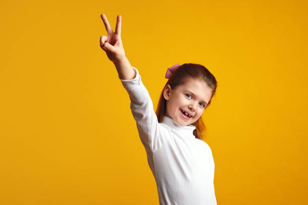 istock Cute kid making peace gesture with raised hand against yellow background 1320655085