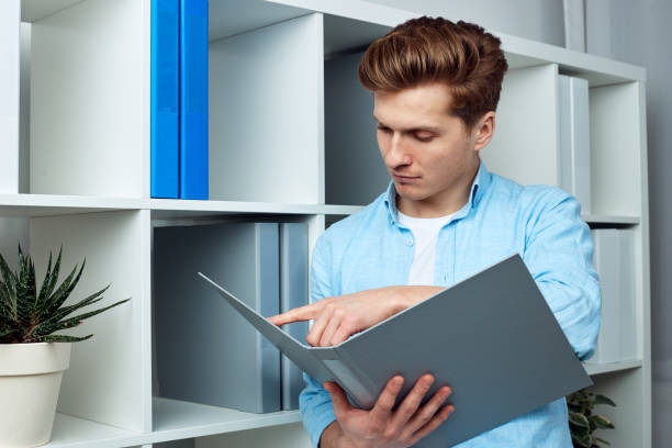 istock Young man holding document file, trying to find some important information 1320655103