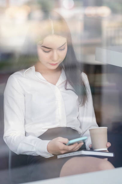 istock Portrait of young businesswoman using smartphone while sitting at office, looking through glass window. 1320657277