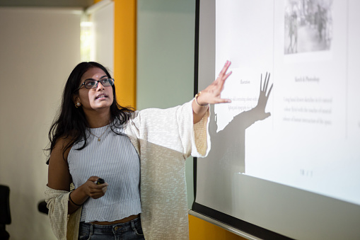 Estudiante universitario asiático está haciendo una presentación frente a la pantalla del proyector photo