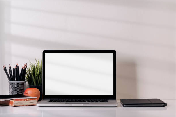 istock Mockup blank screen laptop computer and supplies on white table. 1320658577