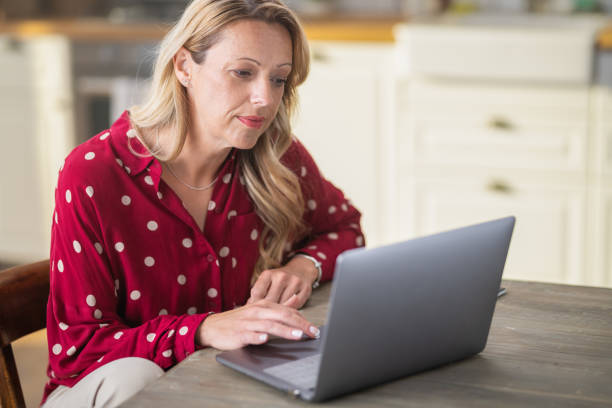istock Beautiful Woman Smiling And Using Laptop While Sitting In Her Kitchen 1320668628