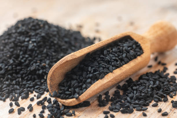 istock Black cumin seeds and wooden scoop, texture background 1320670889