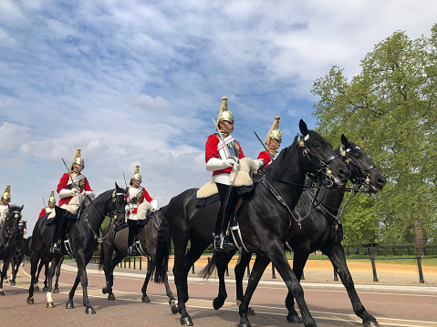 Mounted Coldstream Guards in ceremonial dress on exercise in Hyde Park, London, England, UK. Bright sunny days in the capital city highlight the classical architecture and iconic sites in these outdoors scenes of London in early summer, England, UK