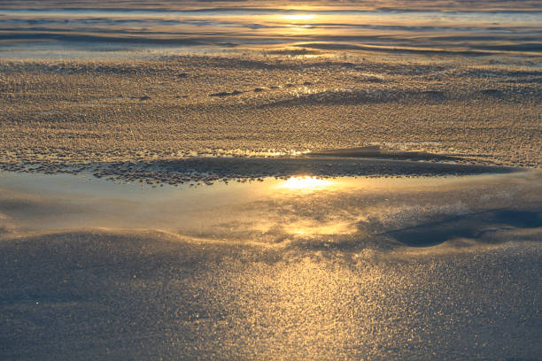 Arctic landscape in winter time. Small river with ice in tundra. Sunset.