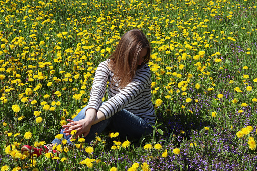 Woman sitting in a field with wildflowers. Summer rural scene.