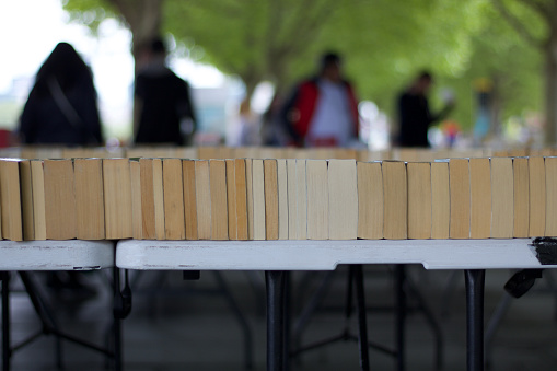 Market stall of paperback books lying on side for sale with copy space and showing blurred people beyond