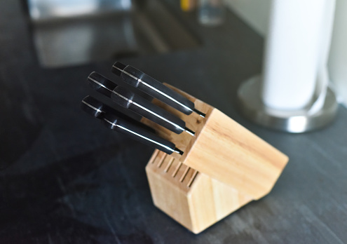 A wooden knife block with an assortment of utensils