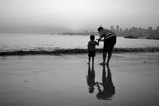 Father with his son showing him the sunset at beach.