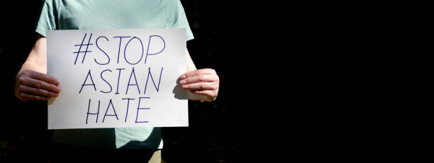 istock Stop asian hate concept. AAPI inscription, text on paper placard in male hands over black background with copy space for text 1320680890