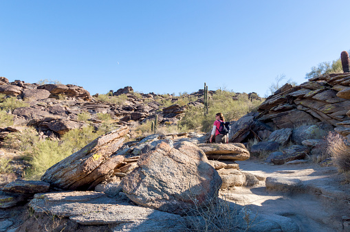 This woman is enjoying a hike through the desert terrain on the Mormon Trail.  This hike is located on South Mountain Park in Phoenix, Arizona and enjoys expansive views and rugged terrain.