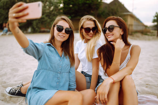 istock Three beautiful woman doing selfie with phone at the beach. 1320686057